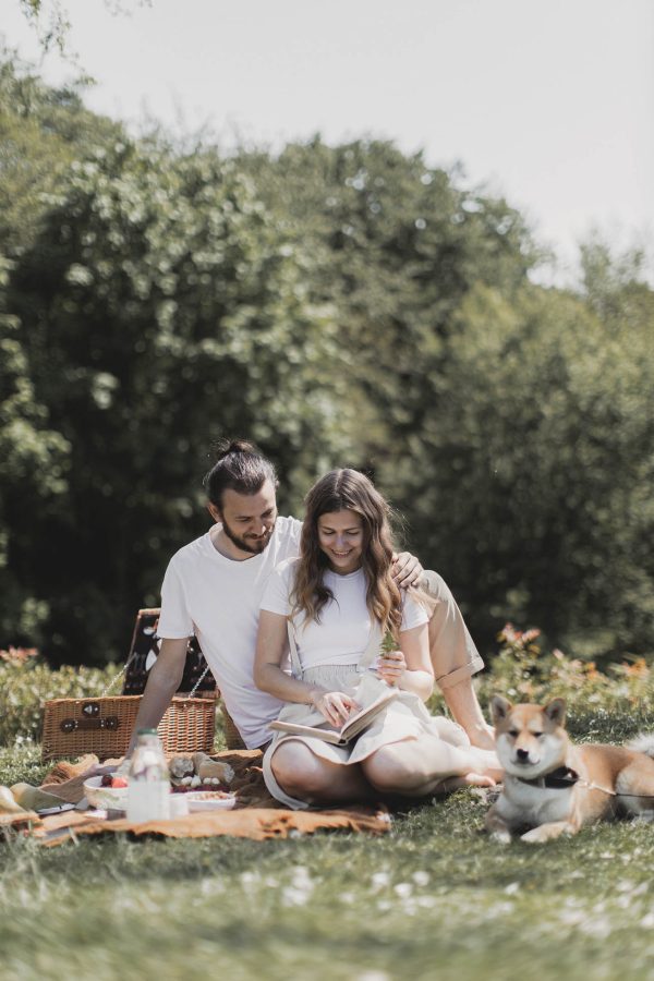 couple sitting on grass with dog and picnic basket at The parcHAUS